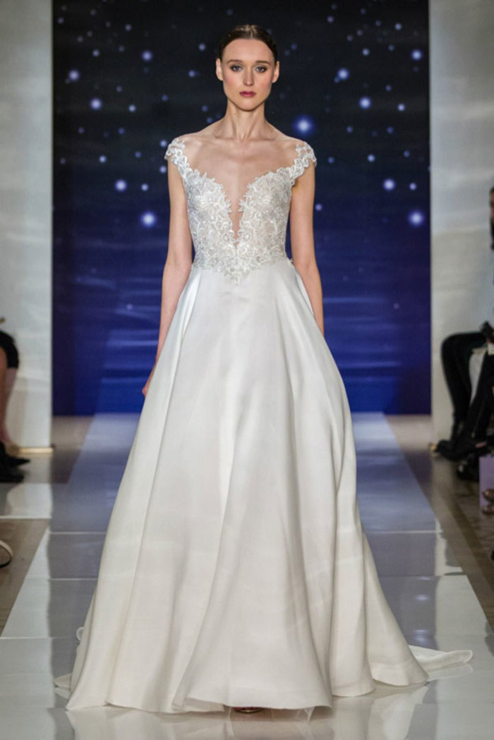 Reem Acra Bridal Spring 2016。雷姆·阿克拉2016纽约婚纱周春夏婚纱发布。本季系列表达了“每一位新娘都是明星”的想法，以闪耀的蕾丝细节融入大部分的婚纱设计，设计师想要达到一种设计的平衡，在繁华的装点之余也有更多真丝绉纱、斜纹布的简约款式。Acra的礼服更多的是对女性性感的一种表达：低胸、紧身的胸衣、透明的薄纱都无限了属于女性最动人的一面，让穿上婚纱的姑娘犹如夜空中那颗最美的星星。