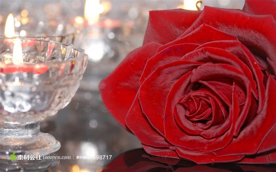 一朵红玫瑰和放着蜡烛的玻璃杯图片