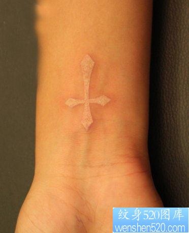 女人手腕处一幅白色图腾十字架纹身图片