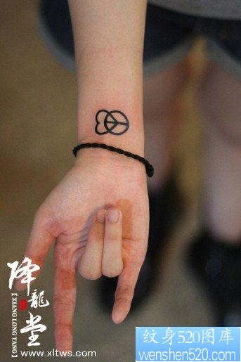 女人手腕小巧的爱心与反战符号纹身图片