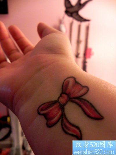 女孩子手腕处小巧的蝴蝶结纹身图片