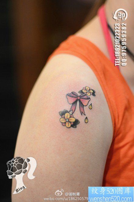 女人肩膀处小巧精美的蝴蝶结花卉纹身图片
