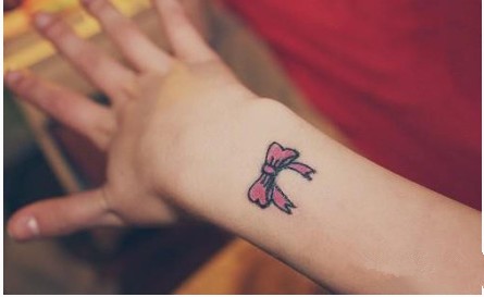 女性手臂小小的红蝴蝶结刺青