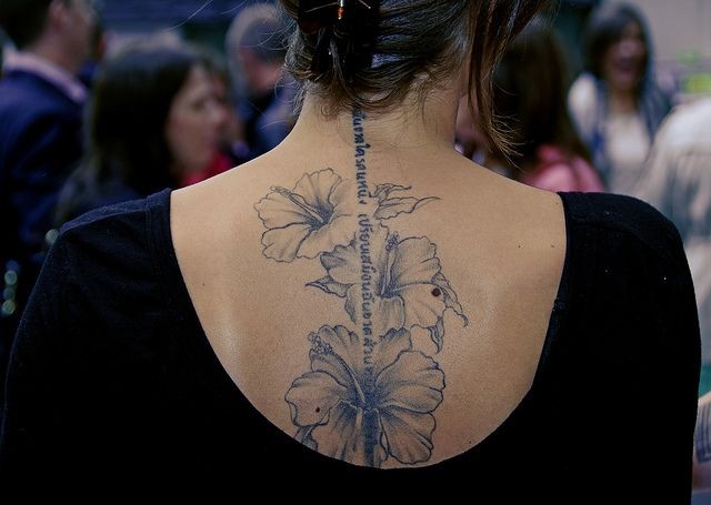 女性背部淡墨色花朵英文纹身