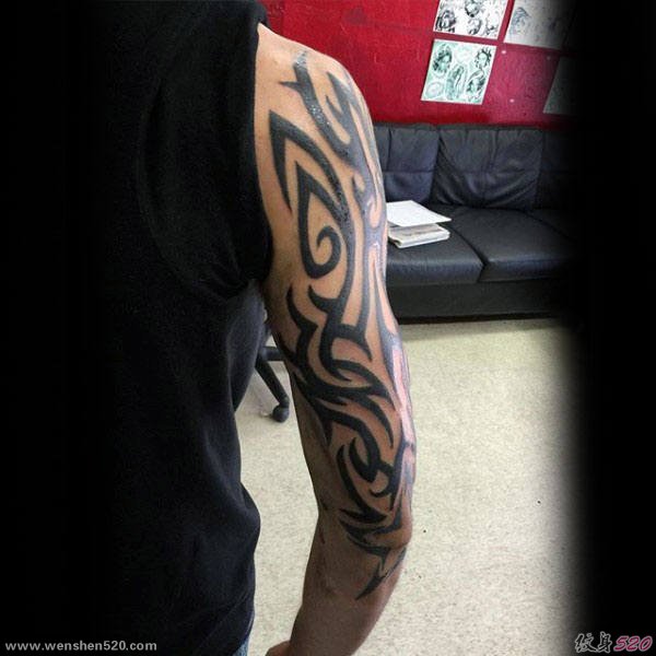 男性大臂膀上强健有力的黑色部落图腾纹身图案