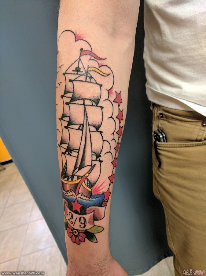 男性手臂上帅气的彩色纹身小帆船图片
