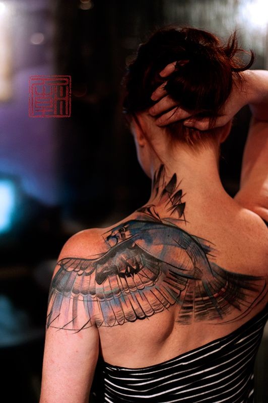 女性背部一只飞翔的大鸟纹身图案