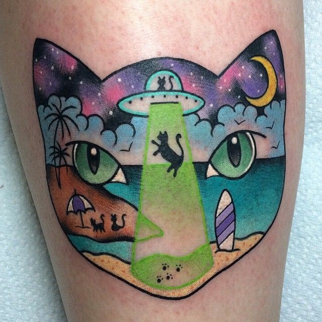 腿部彩色的猫头轮廓与飞船和岛屿纹身图案