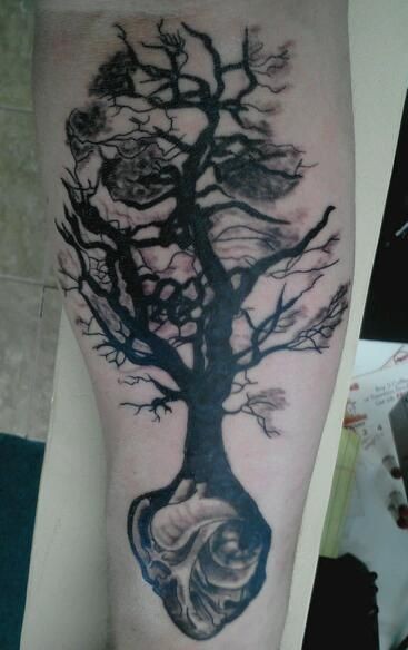 手臂上的黑色树与心脏组合纹身图案