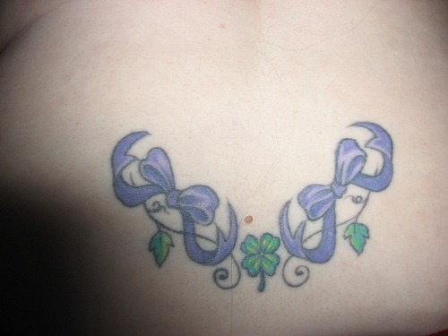 腰部紫色蝴蝶结与四叶草藤蔓纹身图案