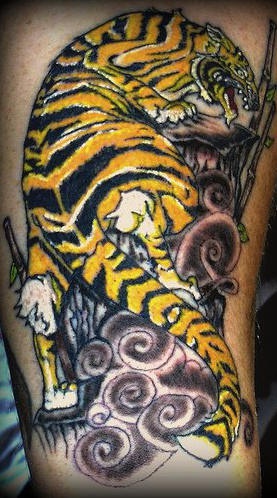 黄色的老虎在岩石上爬行纹身图案