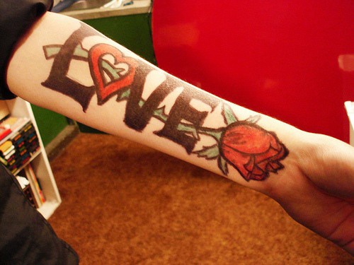 手臂黑色的英文字母与红色玫瑰纹身图案