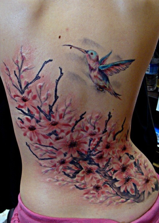 女性背部开花的树和一只蜂鸟纹身图案