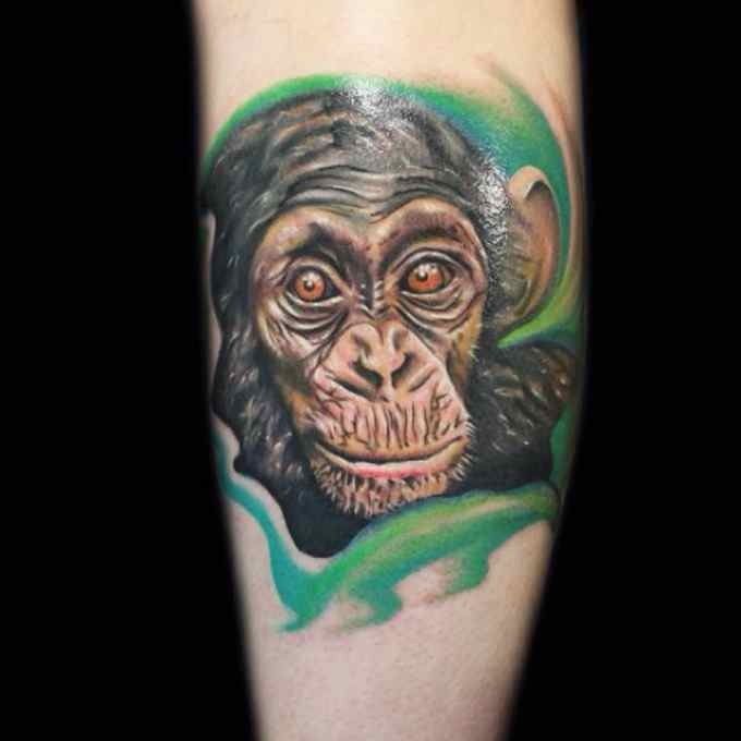 手臂逼真的彩色黑猩猩头像和树叶纹身图案
