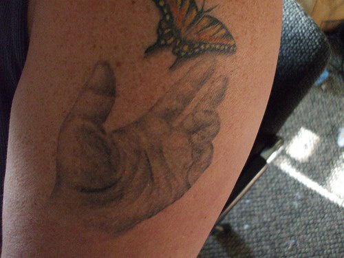 手臂彩色蝴蝶和灰色手纹身图案