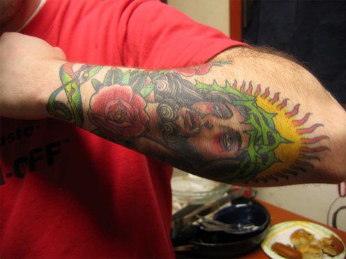 手臂彩色的耶稣肖像和花朵纹身图案