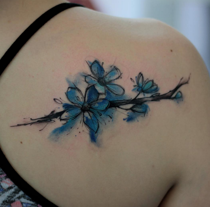 背部水彩风格的蓝色花朵树枝纹身图案