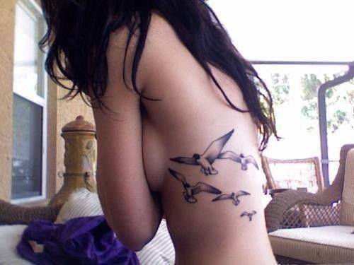 女性腰部黑灰色的小鸟纹身图案
