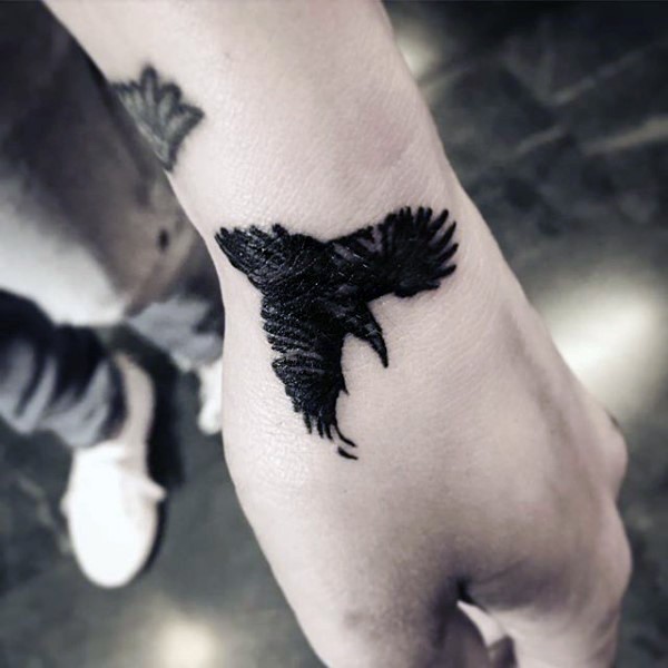 手腕上小小的黑色乌鸦纹身图案