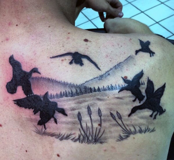 背部黑色的飞鸭和风景纹身图案