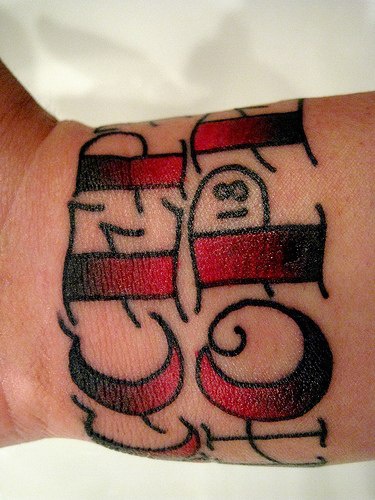 手腕上的黑色和红色字母纹身图案
