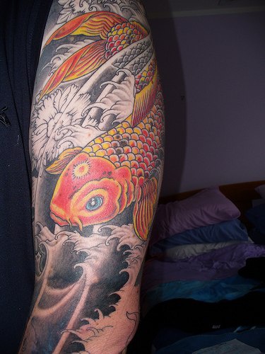 手臂黄金锦鲤和黑色浪花纹身图案