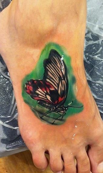 脚背绿色背景中的蝴蝶纹身图案