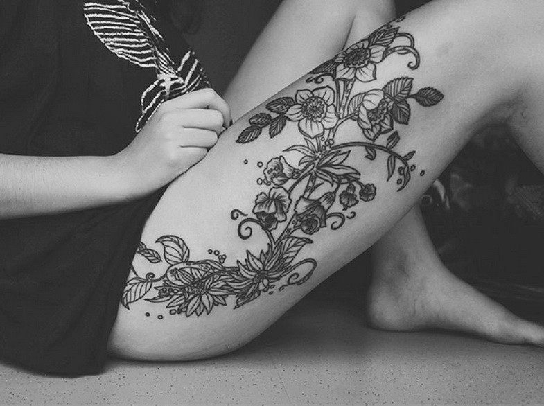 女性腿部黑色和白色的野花纹身图案