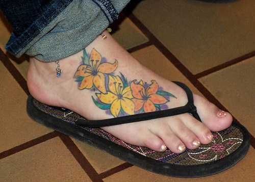 女性脚背上的黄色和橙色花朵纹身