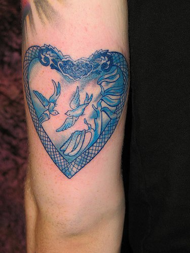 手臂彩色鸽子在心型图案的纹身