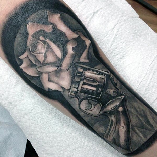 手臂灰色逼真的老左轮手枪和玫瑰纹身