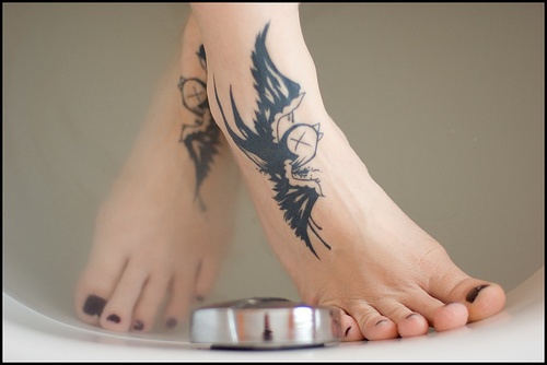女性脚背上的黑色燕子纹身图案