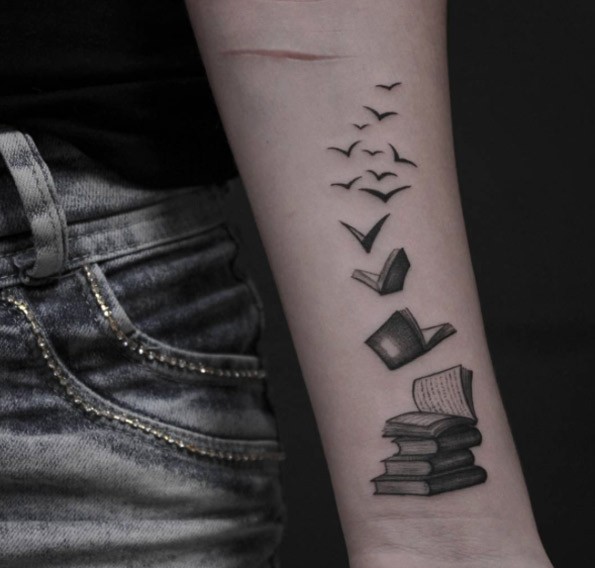 手臂苍白的书籍与成群的小鸟纹身图案