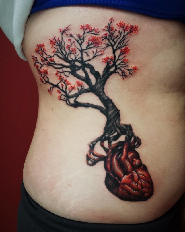 女性侧肋心脏和开红花的树纹身图案