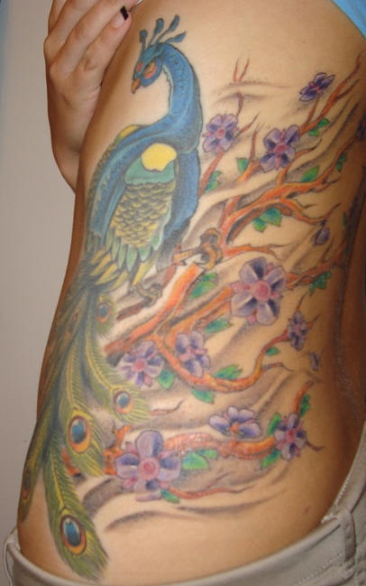 女性腰侧彩色孔雀和树纹身图案