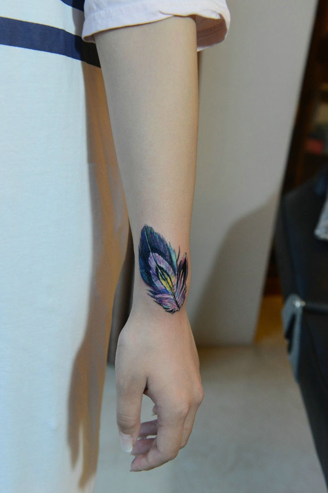 女生手腕上个性十足的彩色羽毛纹身图案