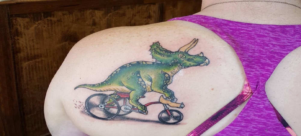 女生后肩上彩绘简单线条自行车和动物恐龙纹身图片