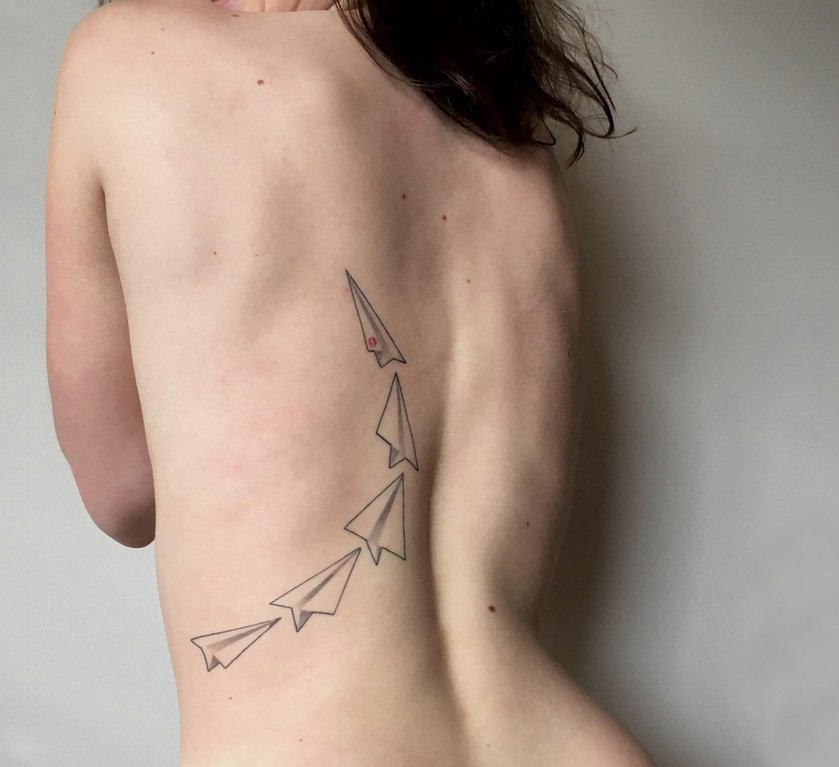 女生后背上黑色点刺几何简单线条纸飞机纹身图片