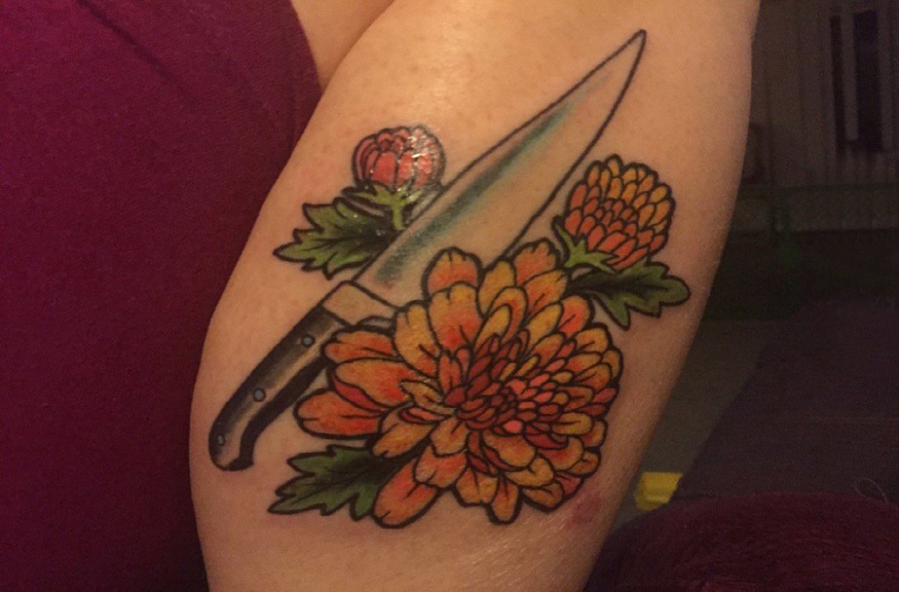 女生大臂上彩绘渐变简单线条匕首和植物花朵纹身图片