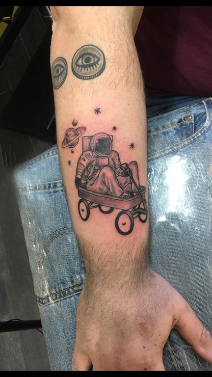 宇航员纹身图案 男生手臂上坐推推车里的宇航员纹身图片
