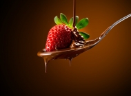 放在倒满巧克力酱勺子里的草莓高清摄影