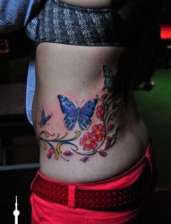 女人腰部漂亮的彩色蝴蝶花卉藤蔓纹身图片