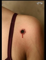 女孩子肩膀处潮流的滴血的弹孔纹身图片