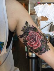女性左手臂上彩色的蛇和玫瑰花纹身图片