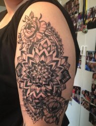 女性左手大臂上遮盖伤疤的精致的花卉纹身图片
