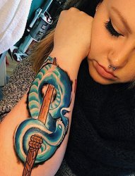 女子手臂上的木剑和蓝色蛇纹身图片
