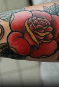 手臂彩色红玫瑰绿叶纹身图案