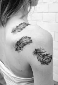 女生肩部飘逸的黑白羽毛纹身图案