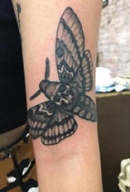 女生手臂上黑色点刺简单线条骷髅型蝴蝶纹身图片